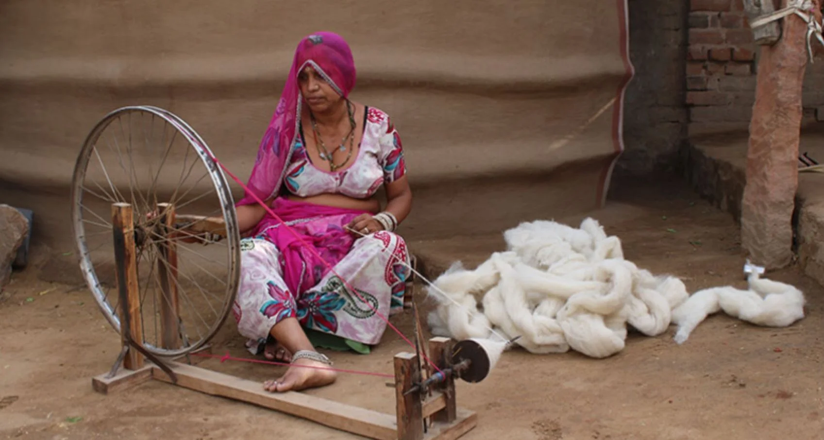 Artisan spinning dyed wool on a traditional wheel